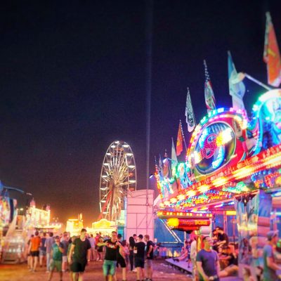 Belebtes Deutsch-Amerikanisches Volksfest Grafenwöhr bei Nacht mit Fahrgeschäften und einem beleuchteten Riesenrad im Hintergrund. — Bild: volksfest-grafenwoehr.de